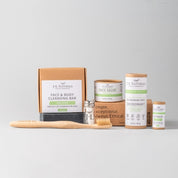 essentials kit with face and skin products in brown and green packaging with whitish grey background