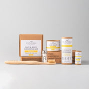 essentials kit with face and skin products in brown and yellow packaging with whitish grey background