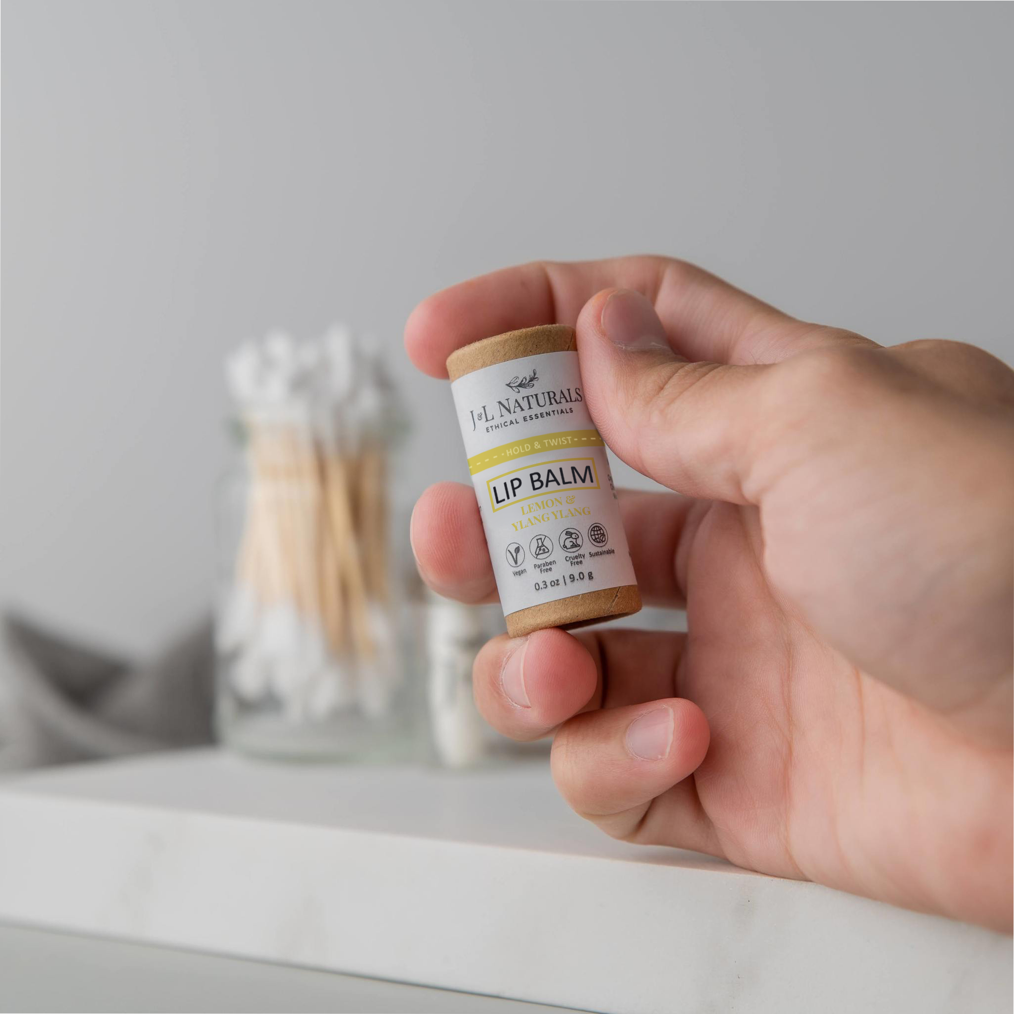 lip balm in brown and yellow packaging held by male hand in white backdrop 