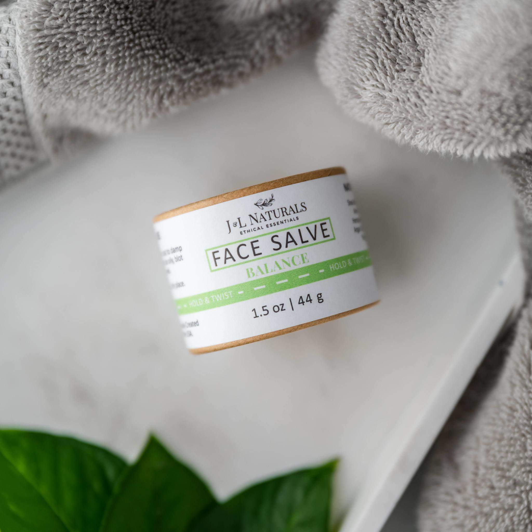 brown and green packaged face salve bundle with white towel background