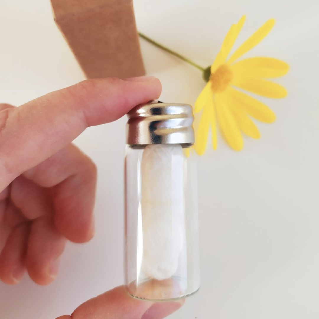 Biodegradable White Charcoal Dental Floss in glass bottle with a hand holding the bottle