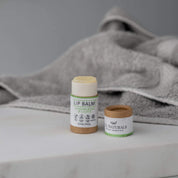 Organic Lip Balm in eco brown packaging Opened with blurred grey towel and white backdrop