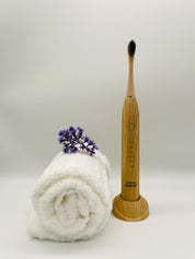 eco friendly bamboo electric toothbrush with a white towel and lavender in a white background