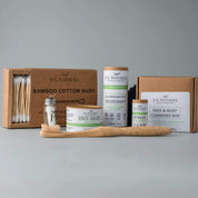 essentials kit with face and skin products in brown and green packaging with whitish grey background