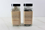 Two Natural Organic Dry Shampoo glass bottles in cute tin packaging with white backdrop close up shot 