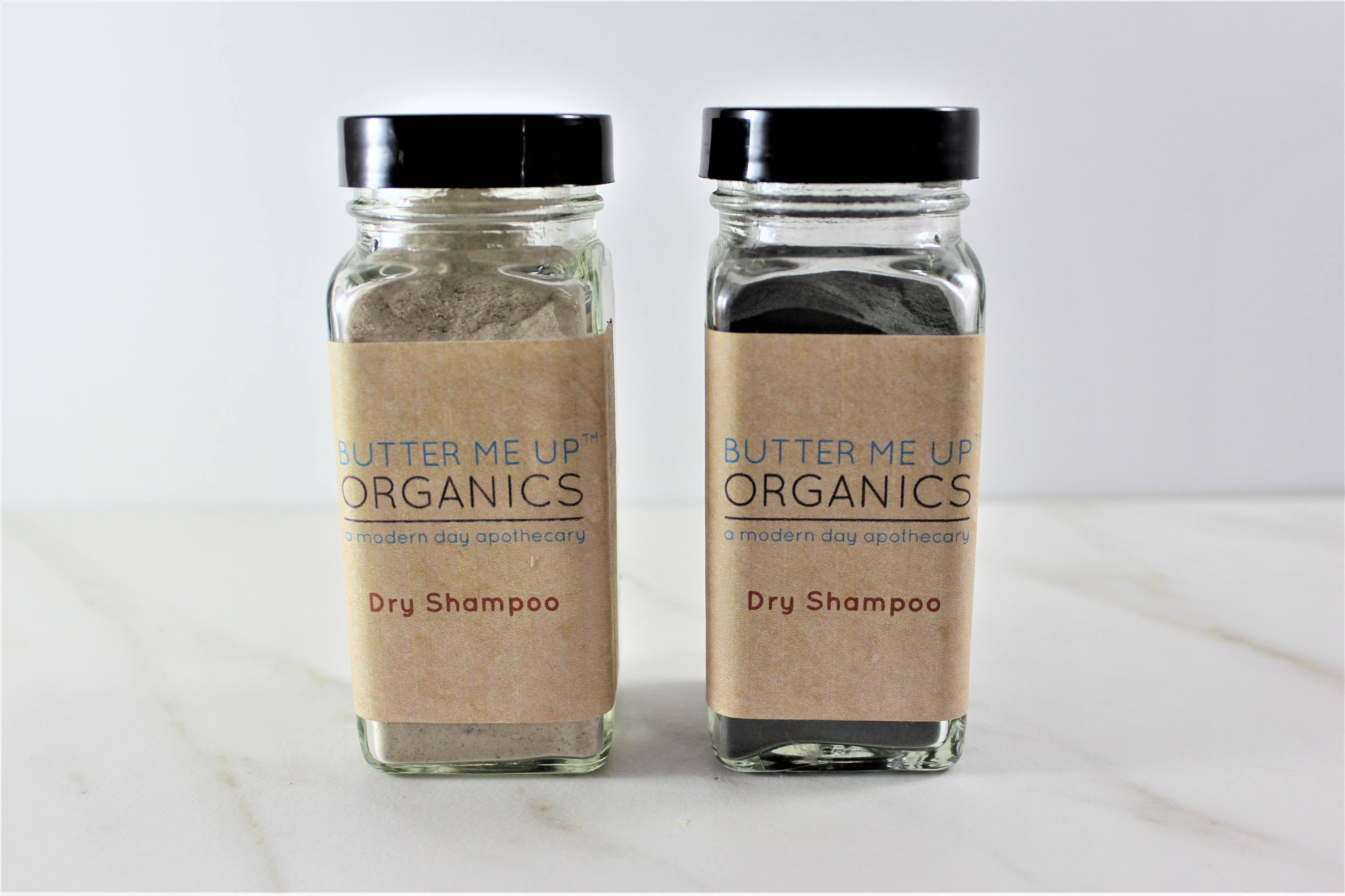 Two Natural Organic Dry Shampoo glass bottles in cute tin packaging with white backdrop close up shot 