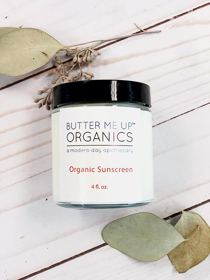 Natural Organic Sunscreen close up product shot with black lid in white background and leaves on the side for visual appeal